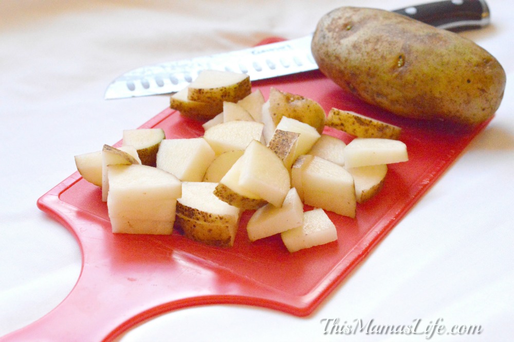 Potatoes cut into chunks on a red cutting board