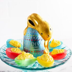 Easter Deviled eggs on a blue cake stand with a chocolate bunny